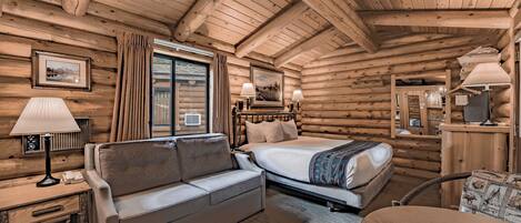 Une chambre aménagée dans un chalet en rondins, avec un canapé, un lit, une table et une lampe.