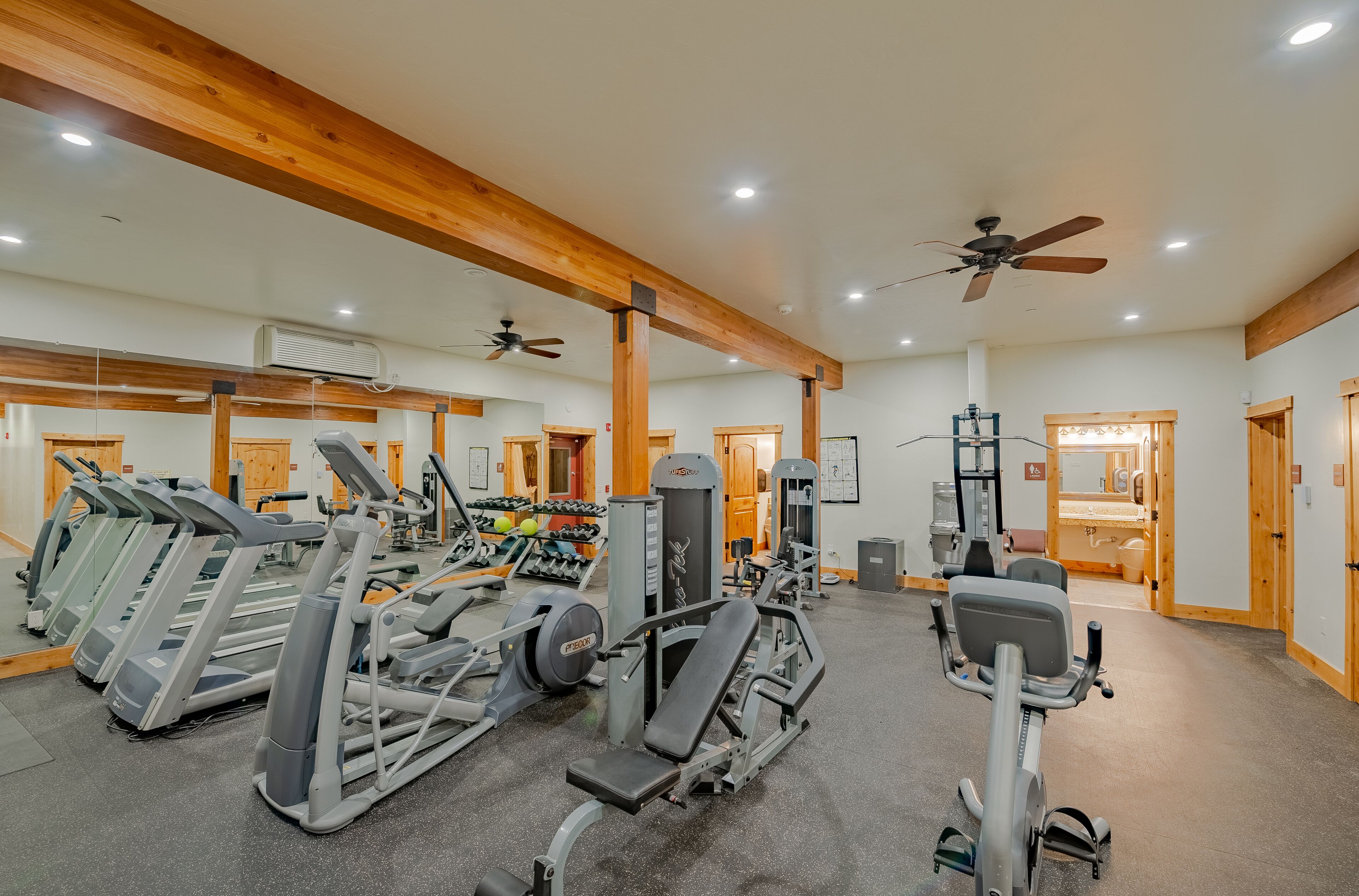 A gym with treadmills, weight machines, and a mirror wall.