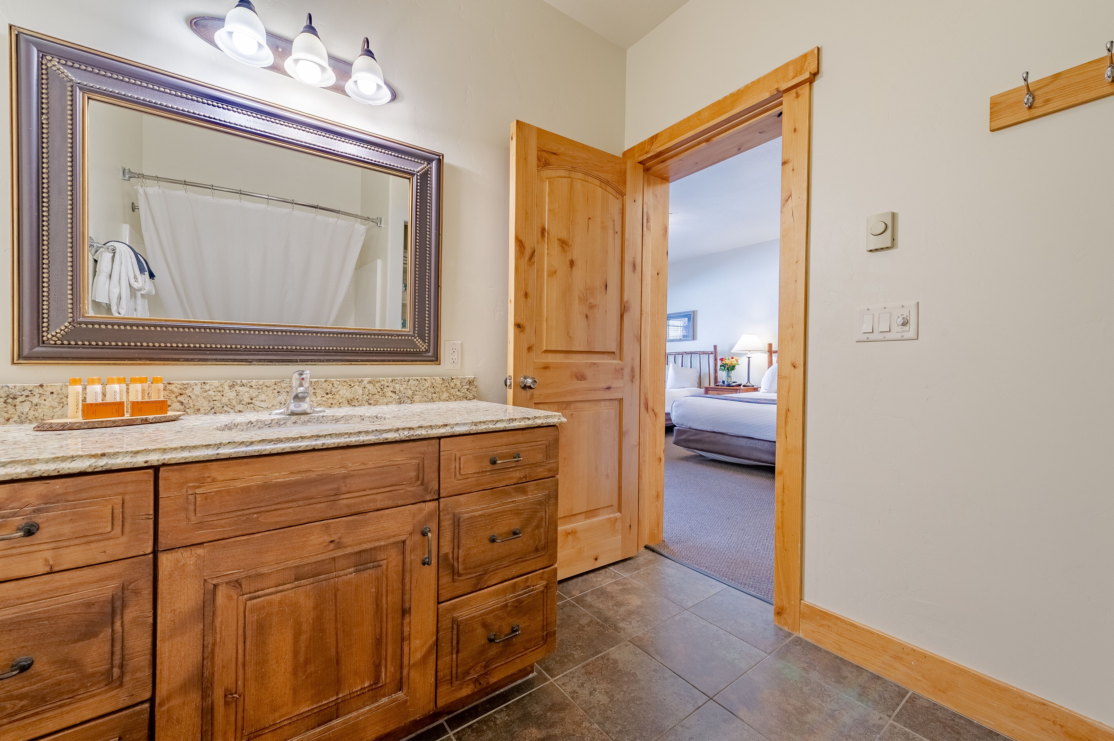 Une salle de bain avec des meubles en bois, un grand miroir et un rideau de douche.