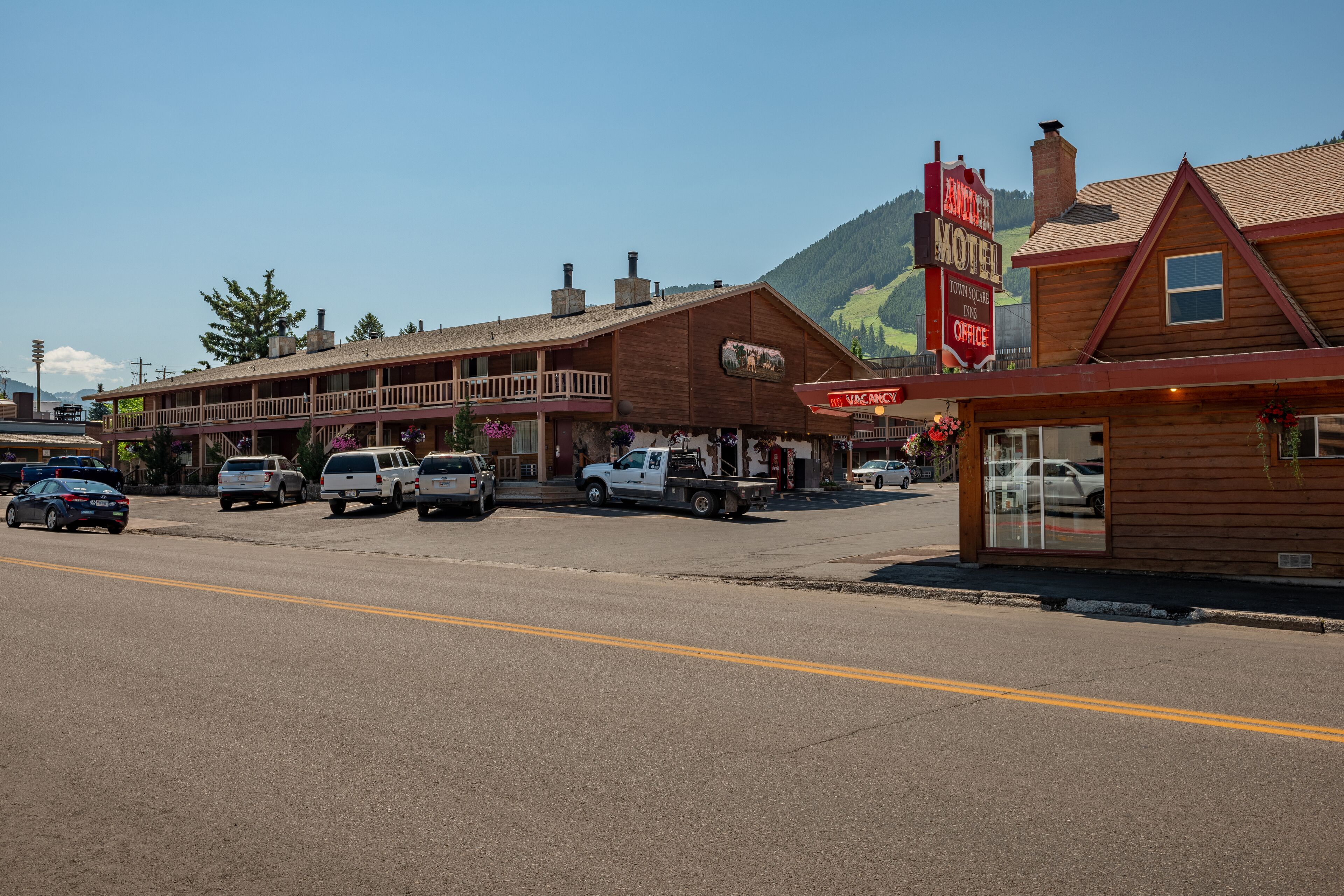 A motel with a large sign, a balcony, and a mountain in the background.