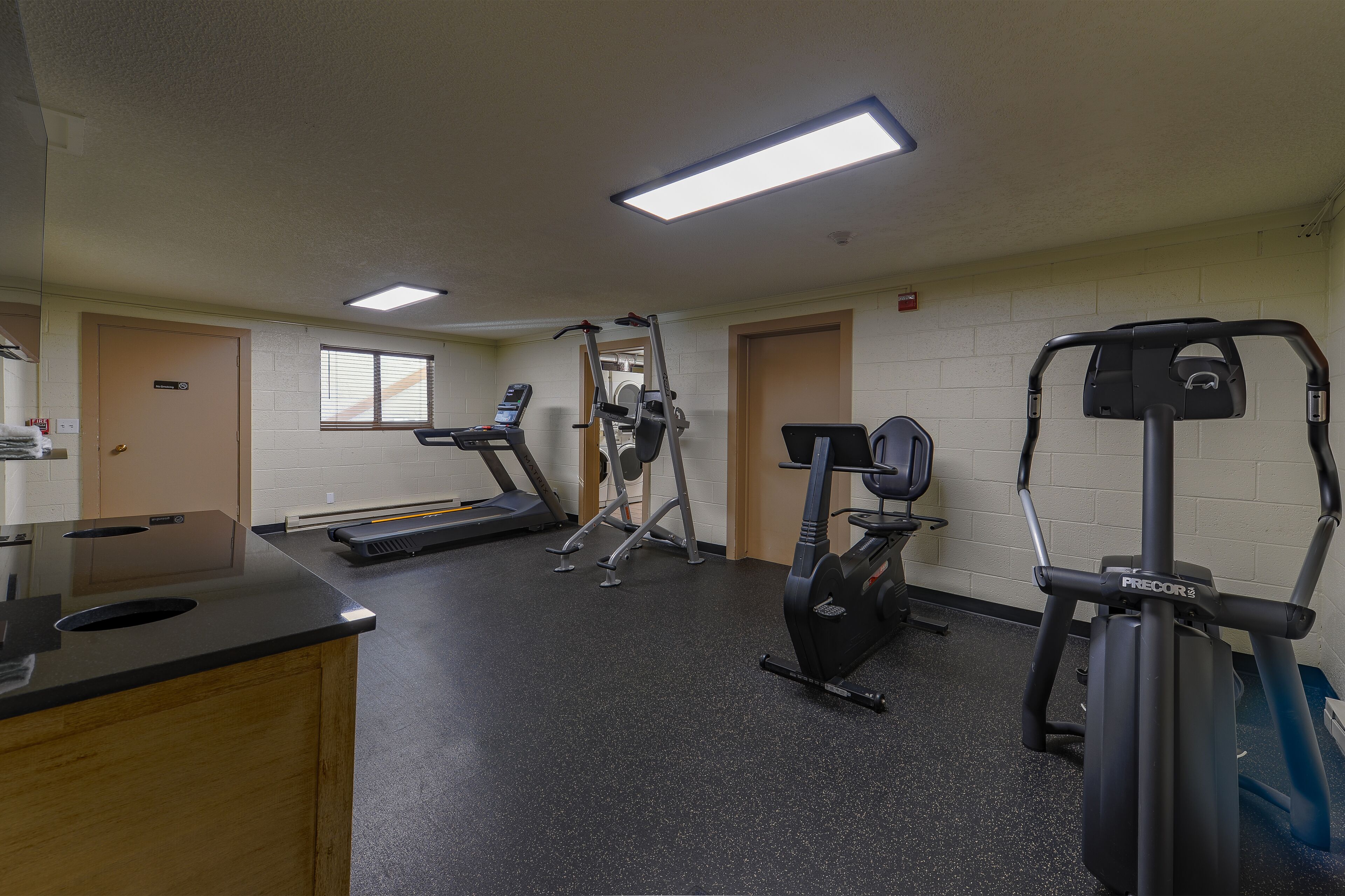 Une salle de sport équipée de tapis de course, d’un appareil elliptique et de machines de musculation.