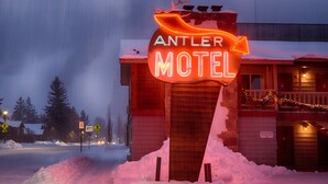 Letrero de motel con una cabeza de venado en la parte superior, rodeado de nieve.