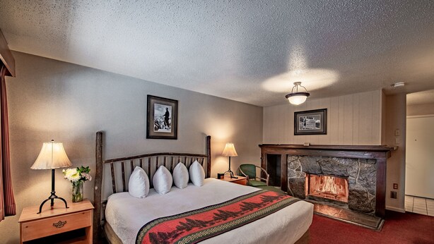 Una habitación de hotel con una cama grande, una chimenea de piedra y dos lámparas fijadas a la pared.
