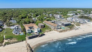 Eine Luftaufnahme eines Küstenresorts mit einem großen Gebäude, das einen Pool, Zugang zum Strand und eine felsige Küstenlinie zeigt.