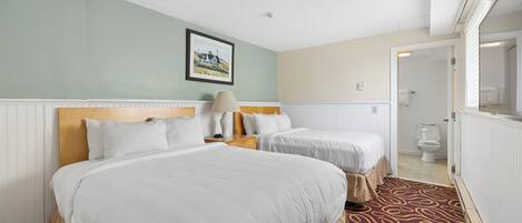 Een hotelkamer met twee bedden, een ingelijst schilderij aan de muur, een lamp op het nachtkastje en een kamer met een patroon.