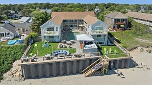 Ein großes Anwesen direkt am Strand mit Pool, Sitzgelegenheiten im Freien und einer überdachten Terrasse.