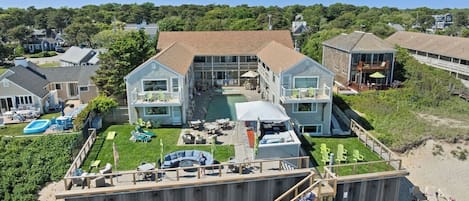 A large beachfront property with a pool, outdoor seating, and a covered patio.
