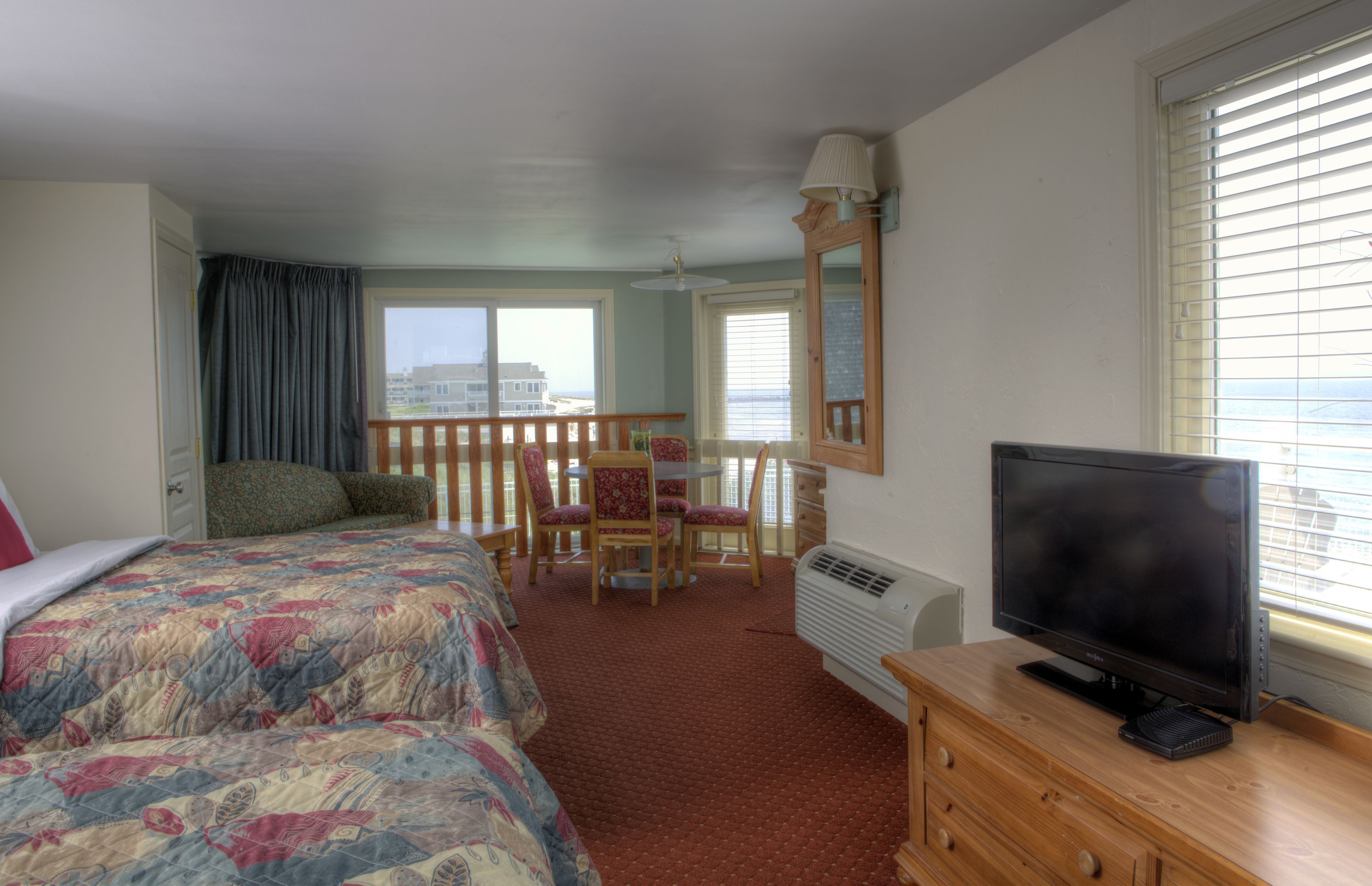 A hotel room with two beds, a TV, a desk, and a chair.