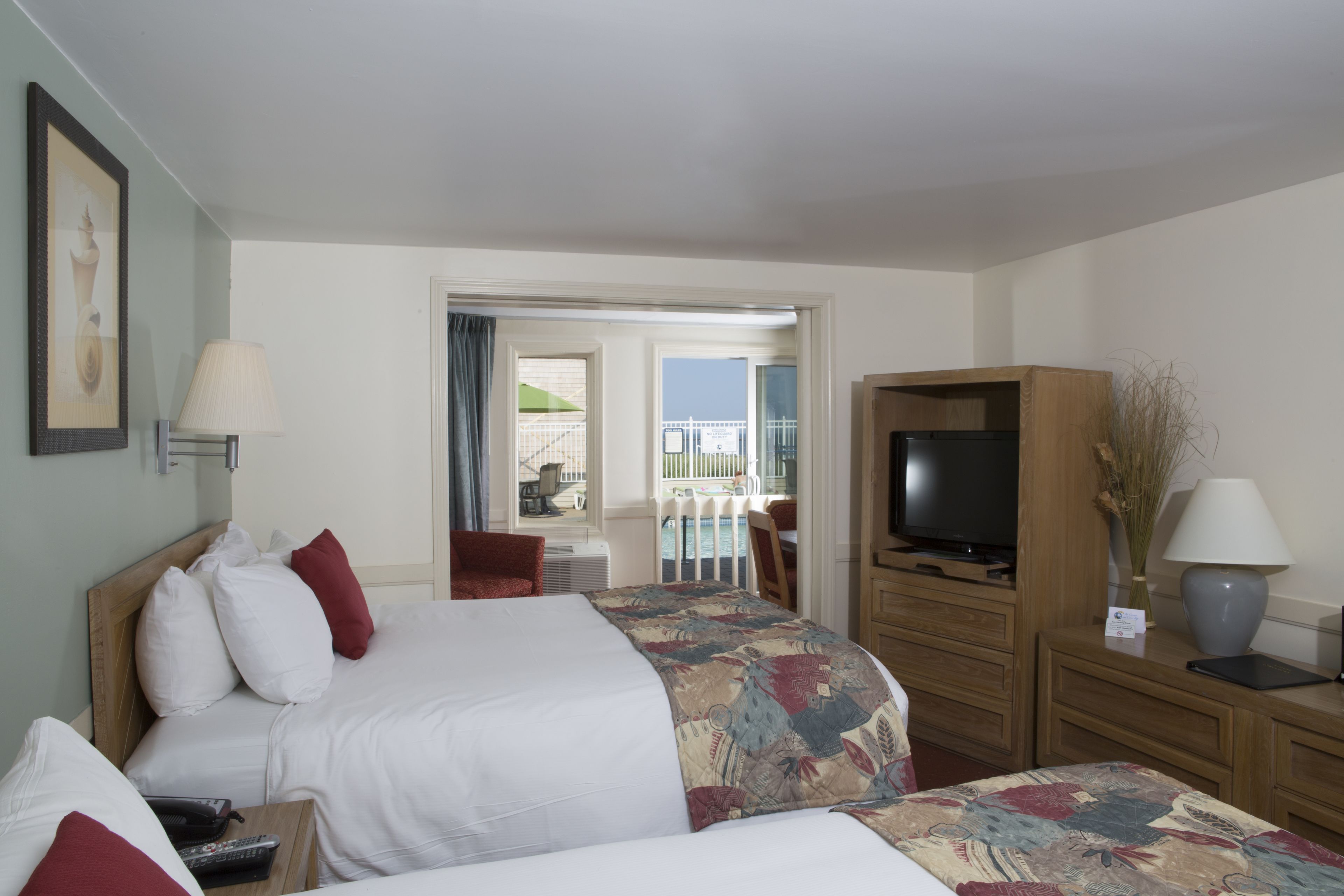 Ein Hotelzimmer mit zwei Betten, einem Fernseher, einem Schreibtisch und einem Balkon mit Blick.