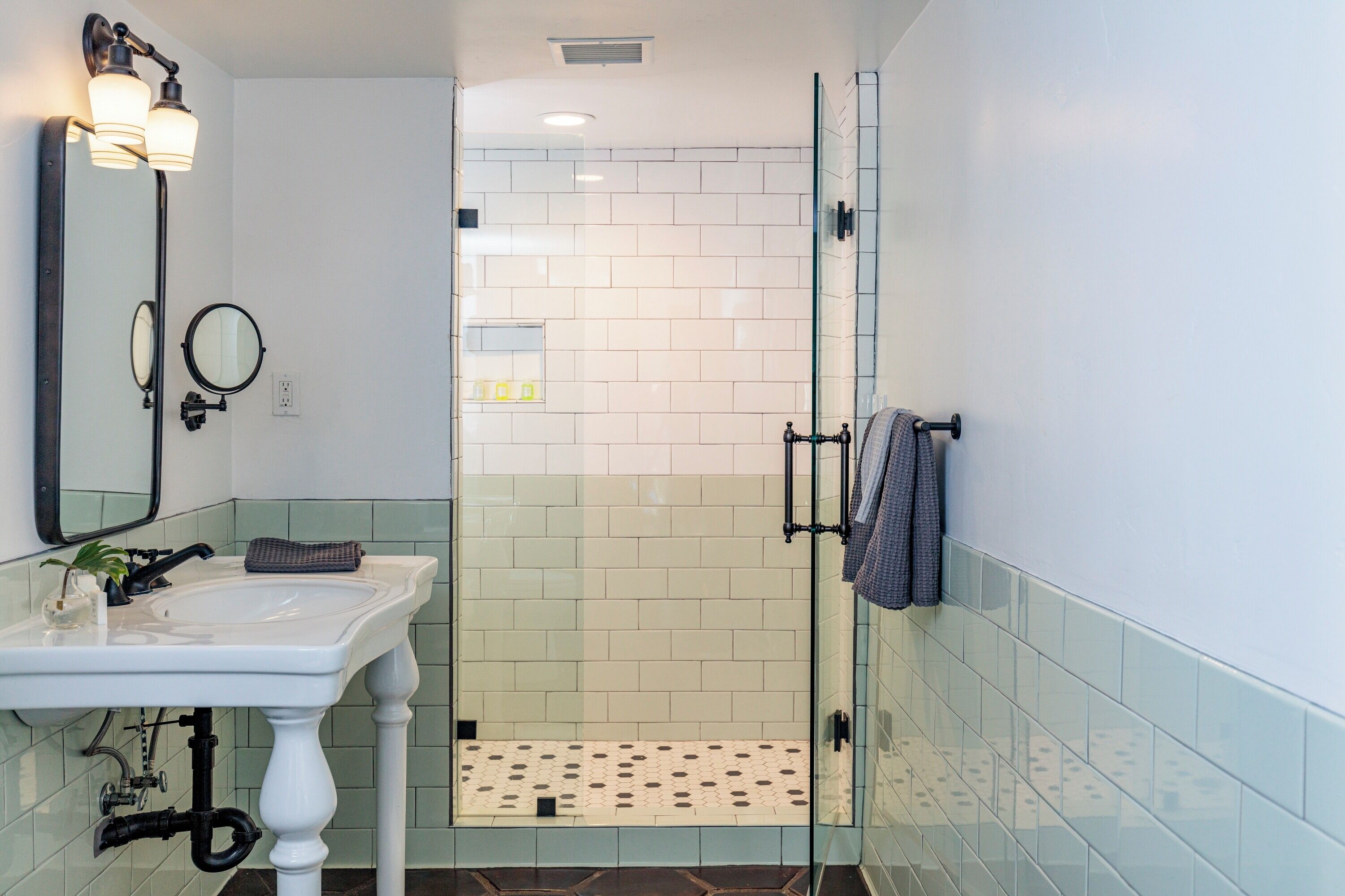A bathroom with a white sink, a mirror, and a glass shower enclosure.