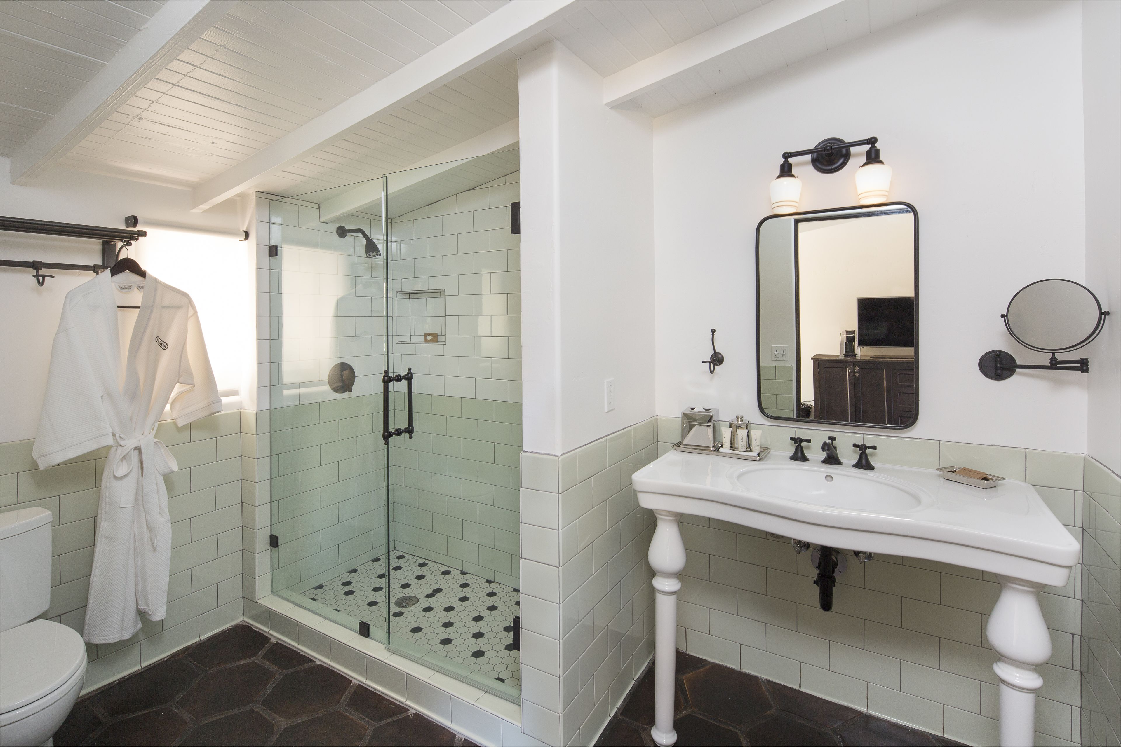A bathroom with a glass-enclosed shower, a white sink, and a mirror with lights.