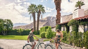 A couple with bicycles parked in front of a building with a sign reading "Angloside Estate." - Ingleside Estate Hotel & Bungalows- Adults Only (Palm Springs)