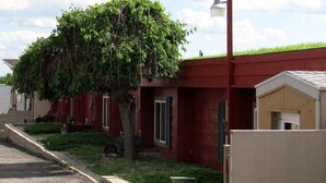 A red building with a tree in front, a lamp post, and a date stamp. - Earth Inn Motel (Jackson)