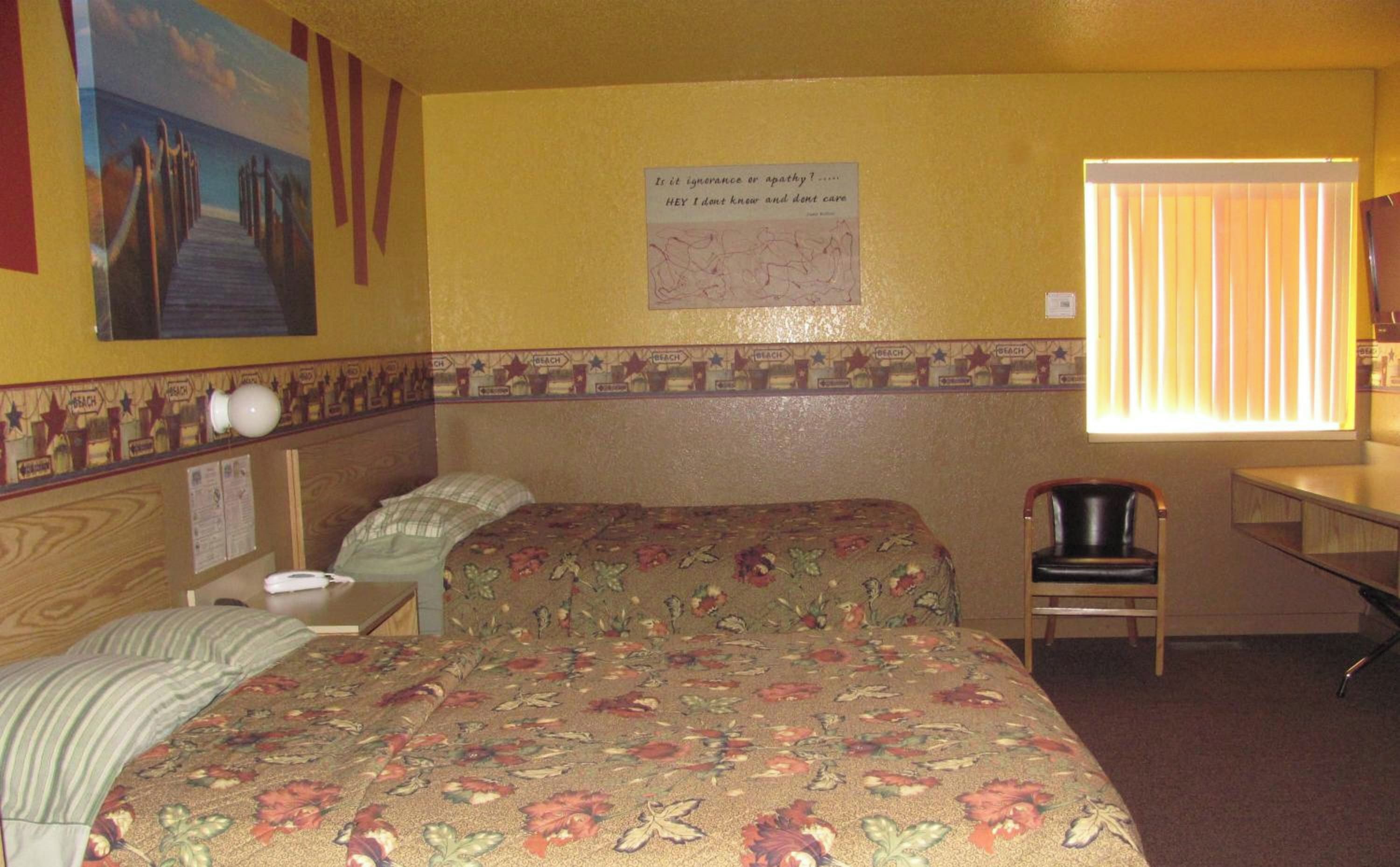 Une chambre d’hôtel avec un lit, une chaise, un bureau et une fenêtre avec des stores.