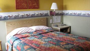 Una cama con colcha estampada, una mesita de noche con lámpara y cuadros con motocicletas.