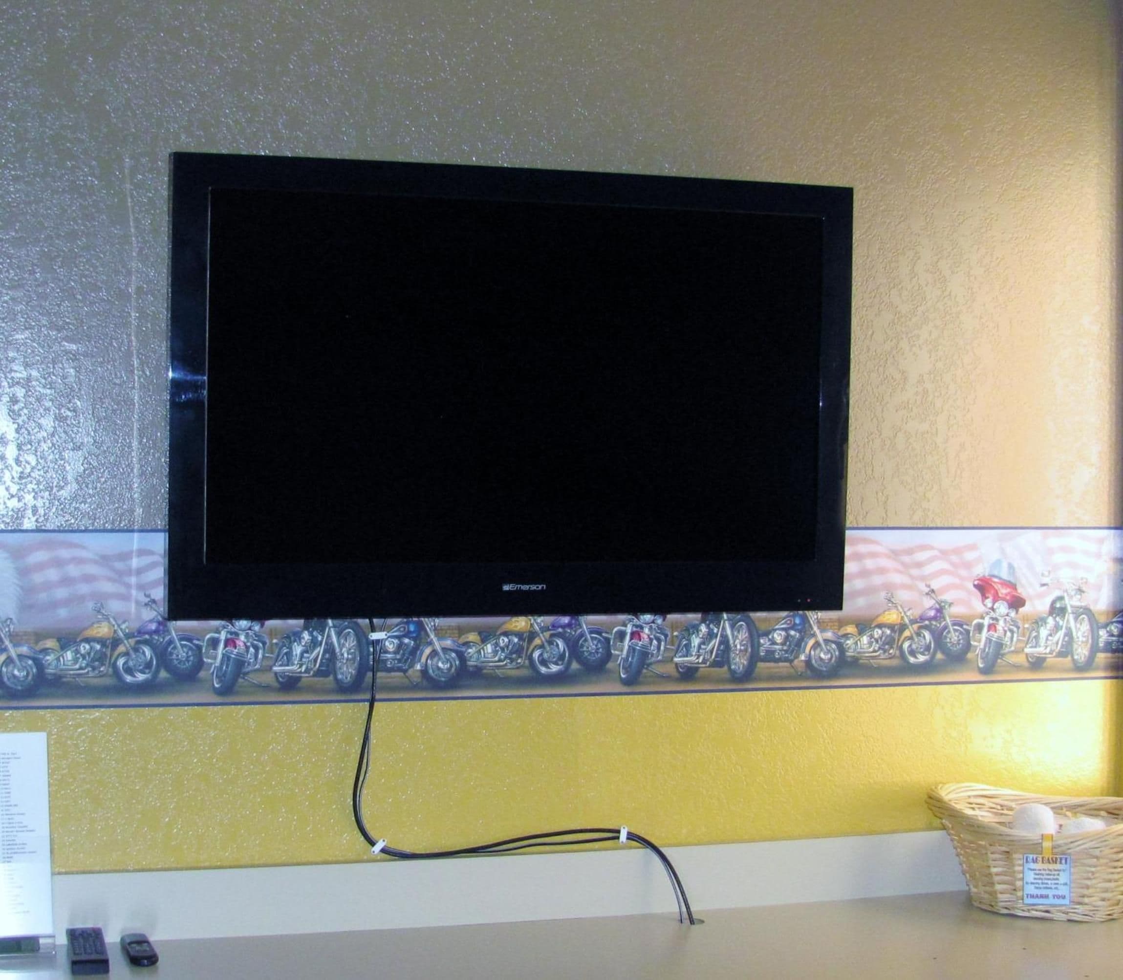 A flat-screen TV mounted on a wall with a decorative border below.