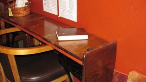 A wooden table with a book on it, a basket with a white cloth, and a chair with a dark cushion. - Earth Inn Motel (Jackson)