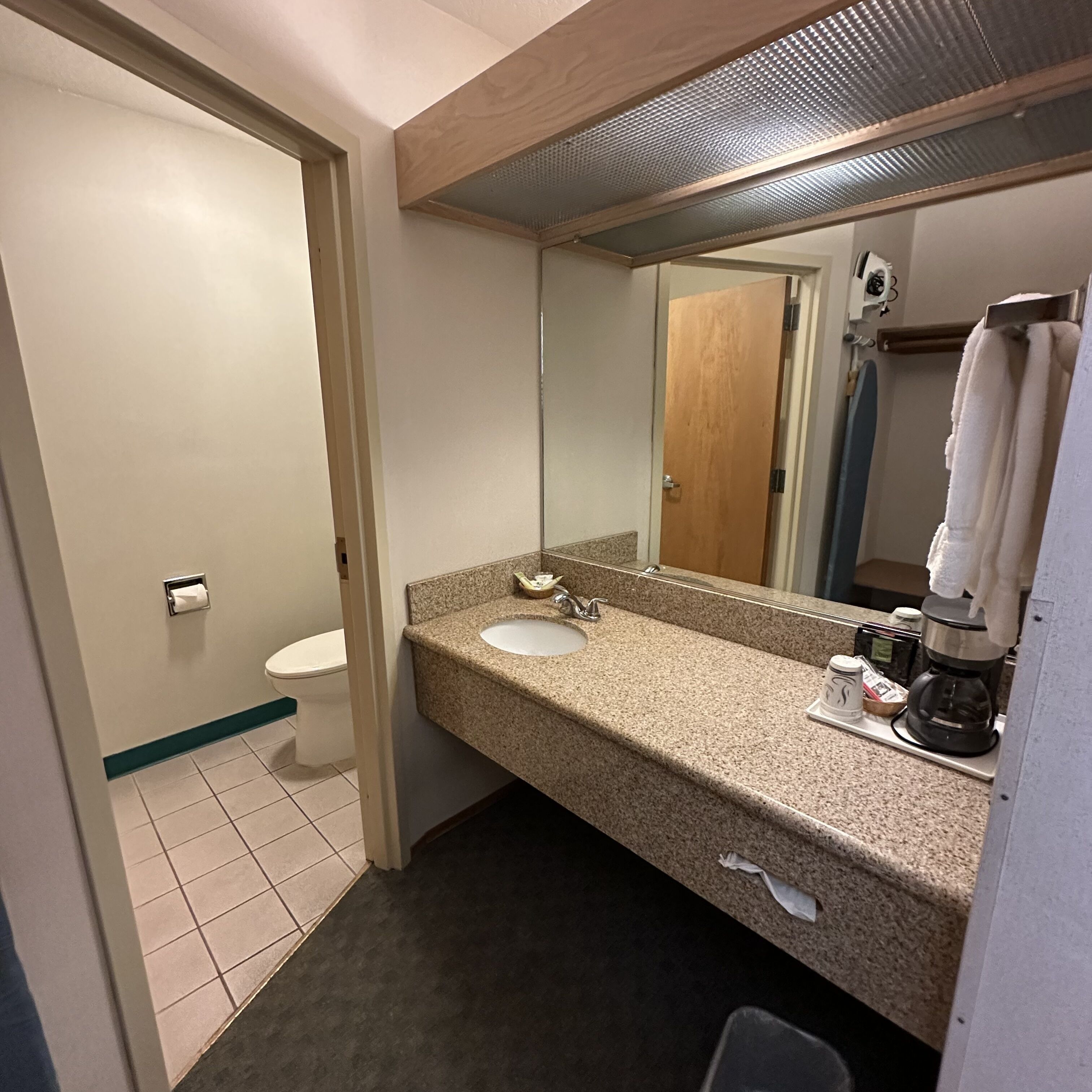 Un baño con lavamanos, espejo e inodoro.