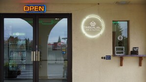 A hotel entrance with a glass door, a neon sign indicating it's open, a night bell sign, and a warning sign about video surveillance. - Timberland Inn & Suites (Castle Rock)