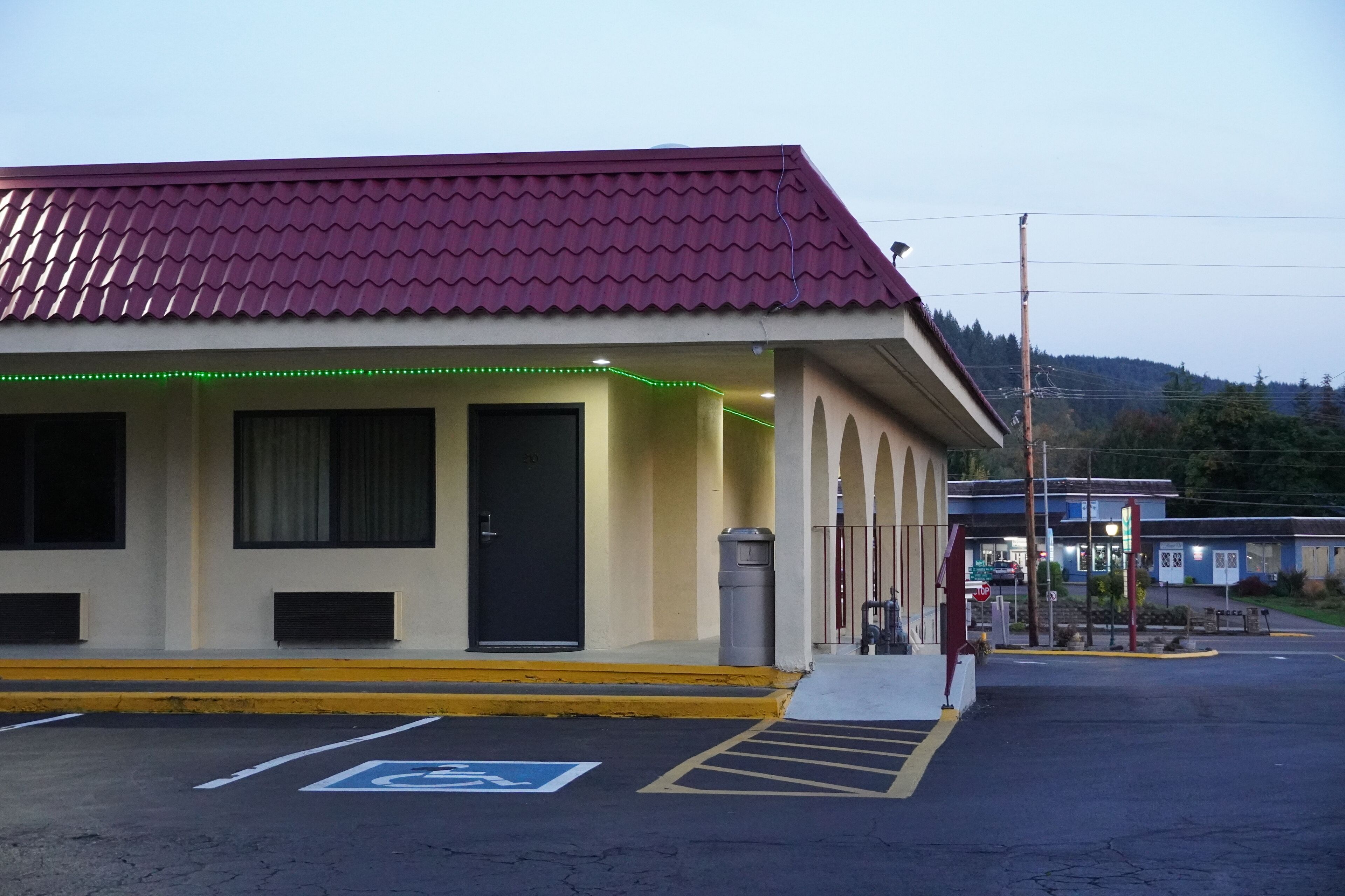 Un edificio con techo rojo, entrada cubierta y zona de estacionamiento con acceso para personas con movilidad reducida.