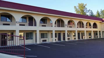 A motel with a row of rooms, each with a balcony and a door.