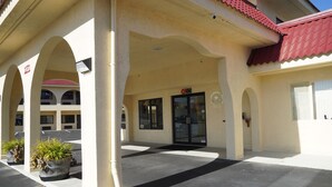 A building with a covered entrance, large columns, and potted plants.