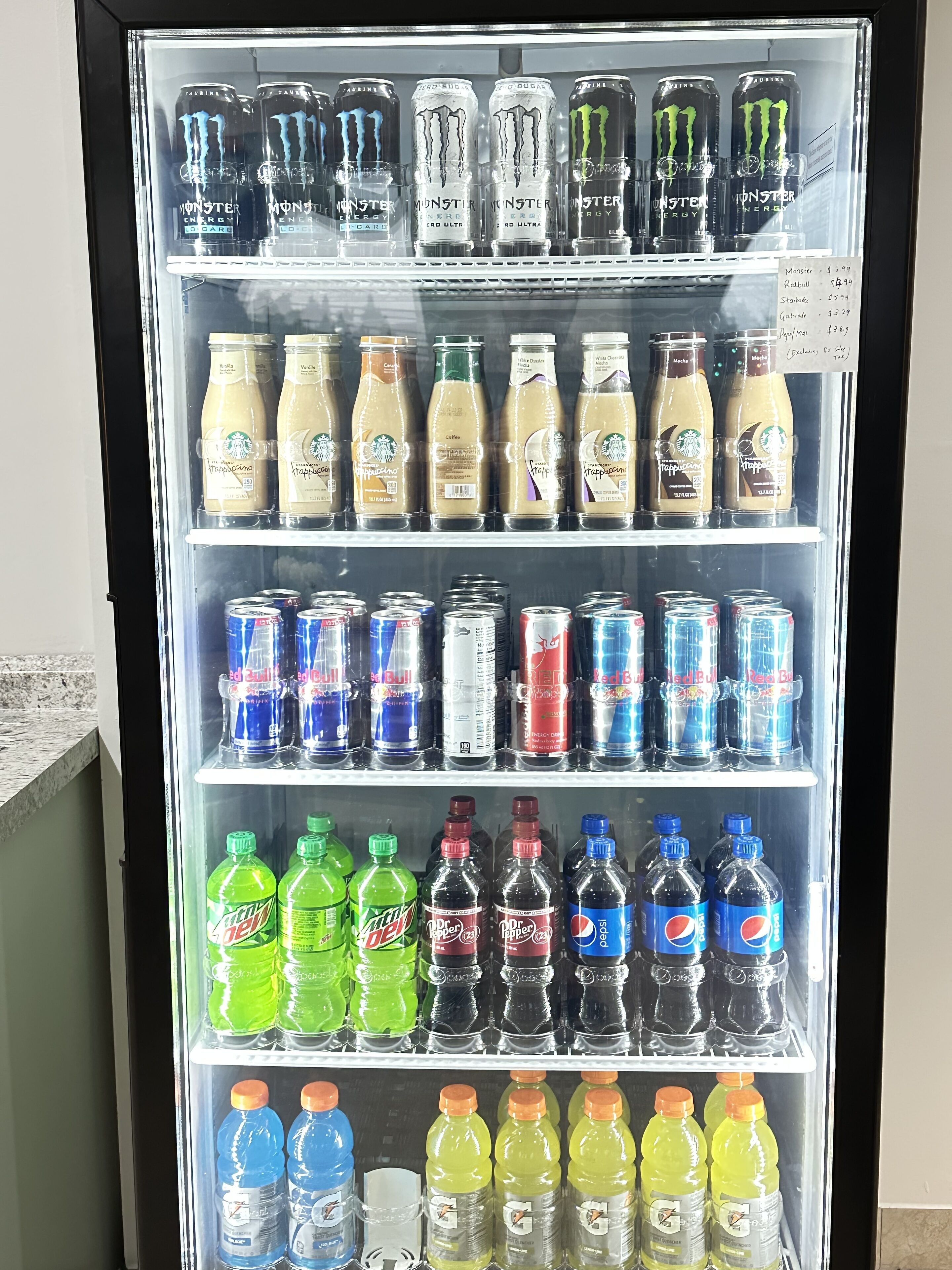 A beverage vending machine stocked with various drinks including Monster Energy, Starbucks, Red Bull, and Mountain Dew.