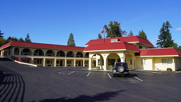A building with a red roof and multiple arches, a parking lot, and a flag.