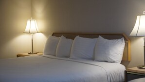 A neatly made bed with white linens, two bedside tables with lamps, and a wooden headboard.