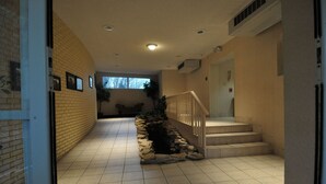 A hallway with a stone planter, a staircase, and a door leading to another room. - Hillside Inn (Madison)