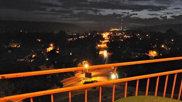 A balcony with a metal railing and a round table with a chair. - Hillside Inn (Madison)