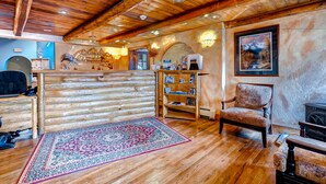 A log cabin interior with wooden floors, a patterned rug, a wooden chair, and a fireplace. - Atrium Condominiums (Breckenridge)