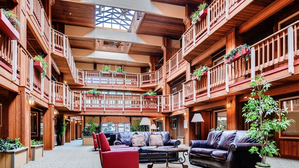 A multi-level wooden atrium with balconies, leather seating, and potted plants. - Atrium Condominiums (Breckenridge)