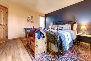 Un dormitorio con una cama de madera, una mesita de noche, una lámpara y una alfombra estampada.