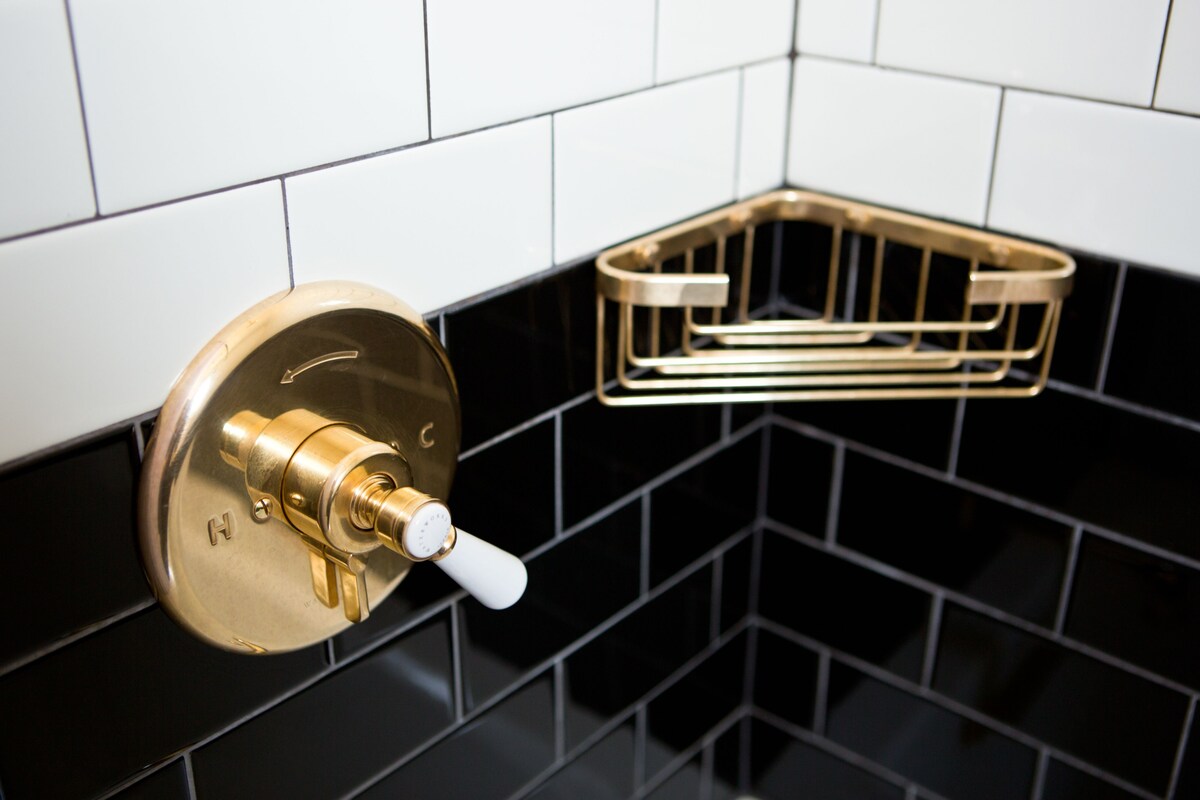 Un baño con grifo y jabonera dorados.