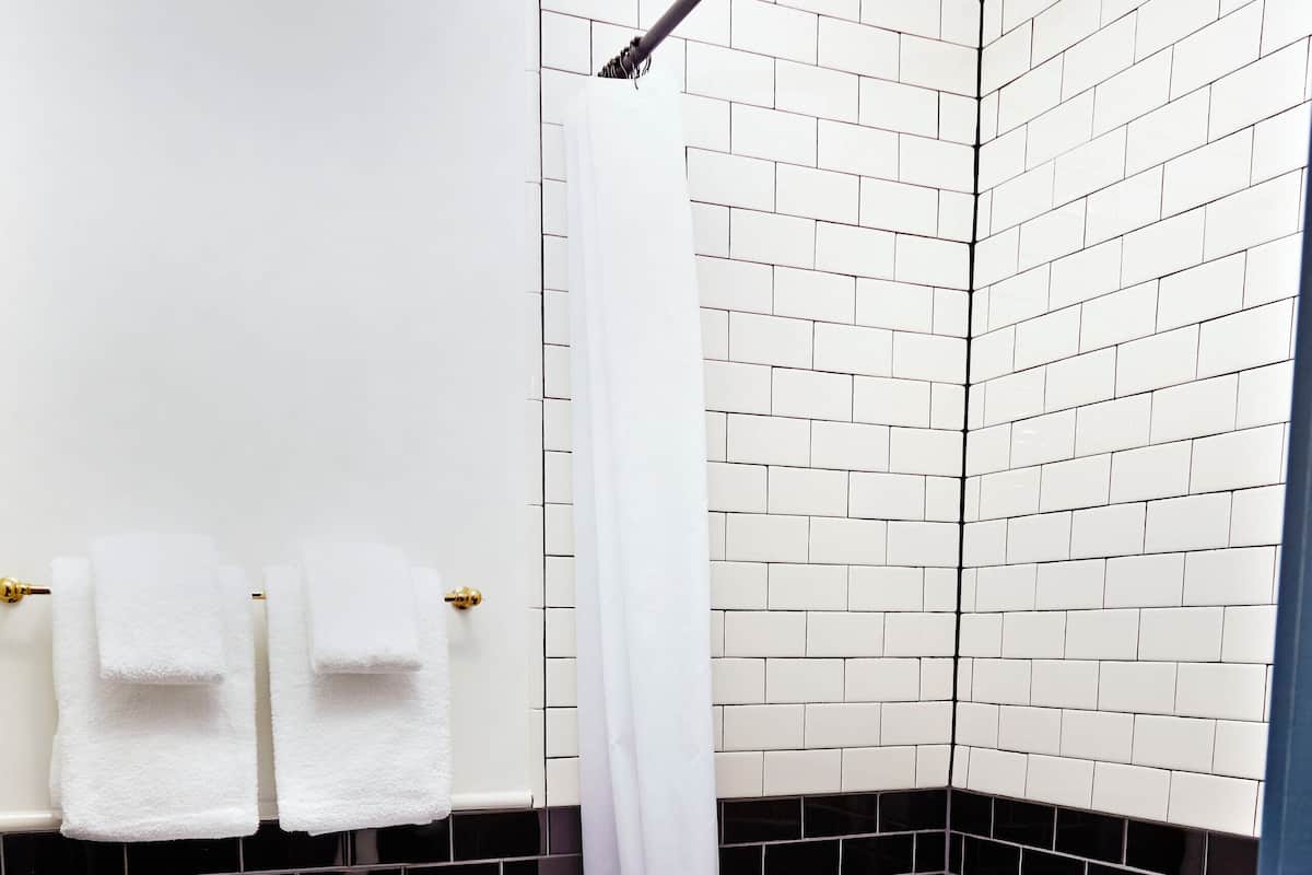 A bathroom with a white toilet, black and white tiled walls, and a shower area.