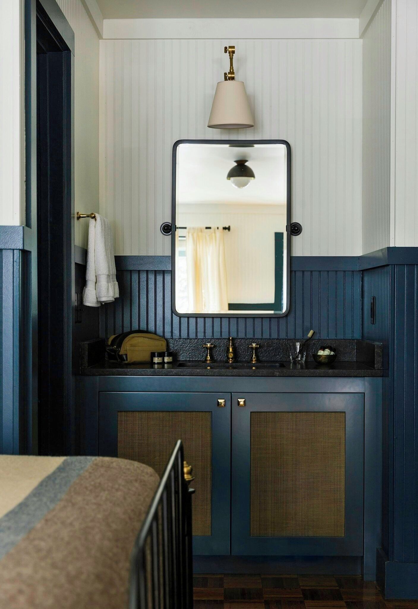 A bathroom with a dark blue vanity, a mirror, a towel rack, and a small sink.