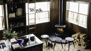 Una habitación acogedora con paredes de madera, una chimenea y un ventanal con cortinas.