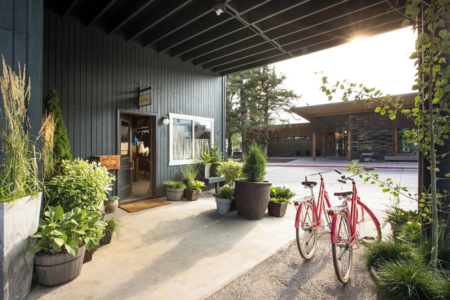 L’entrée d’un hôtel avec une façade en bois, des plantes en pot et un vélo.