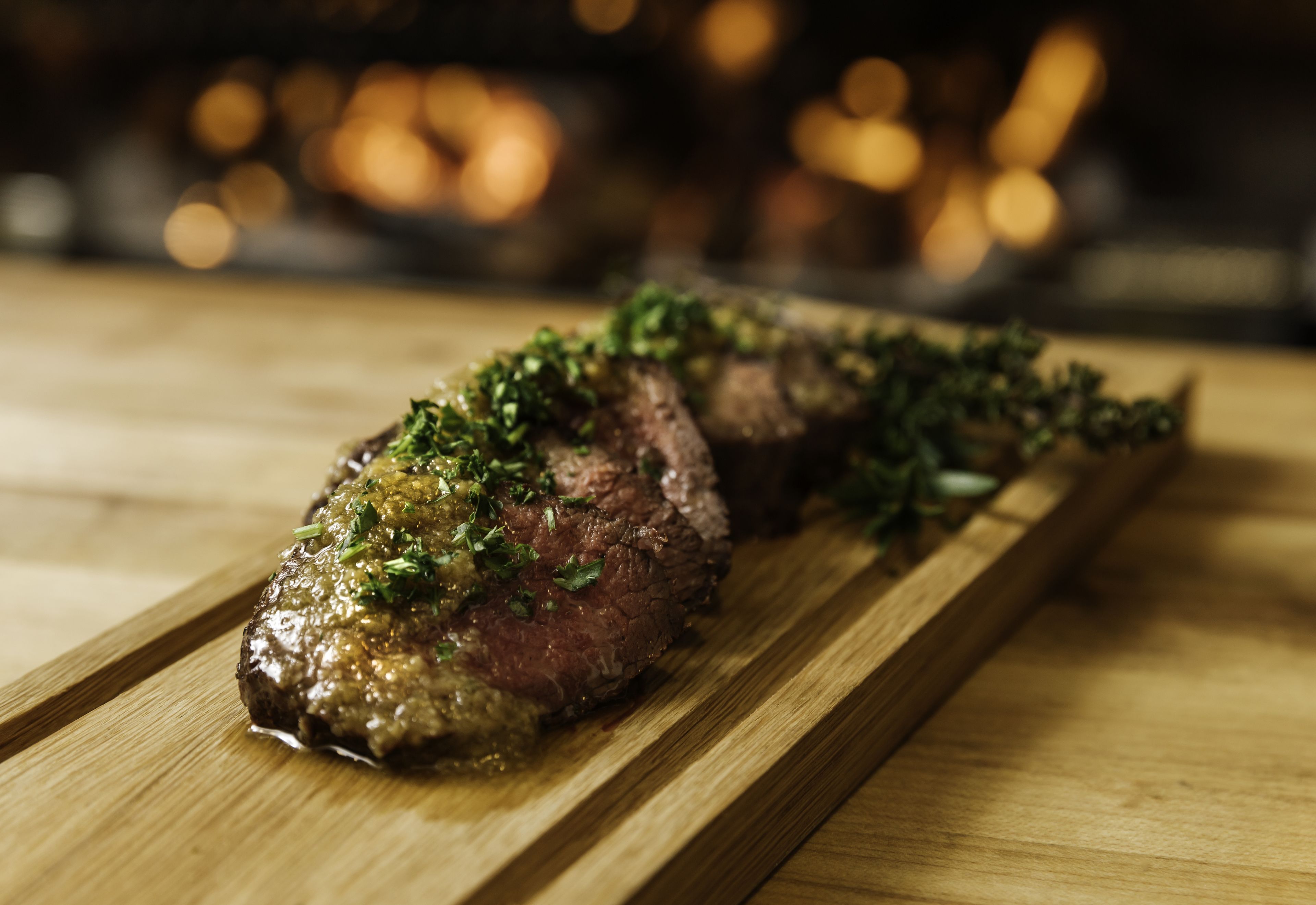 A steak on a wooden board with a blurred background.