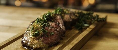 A steak on a wooden board with a blurred background.