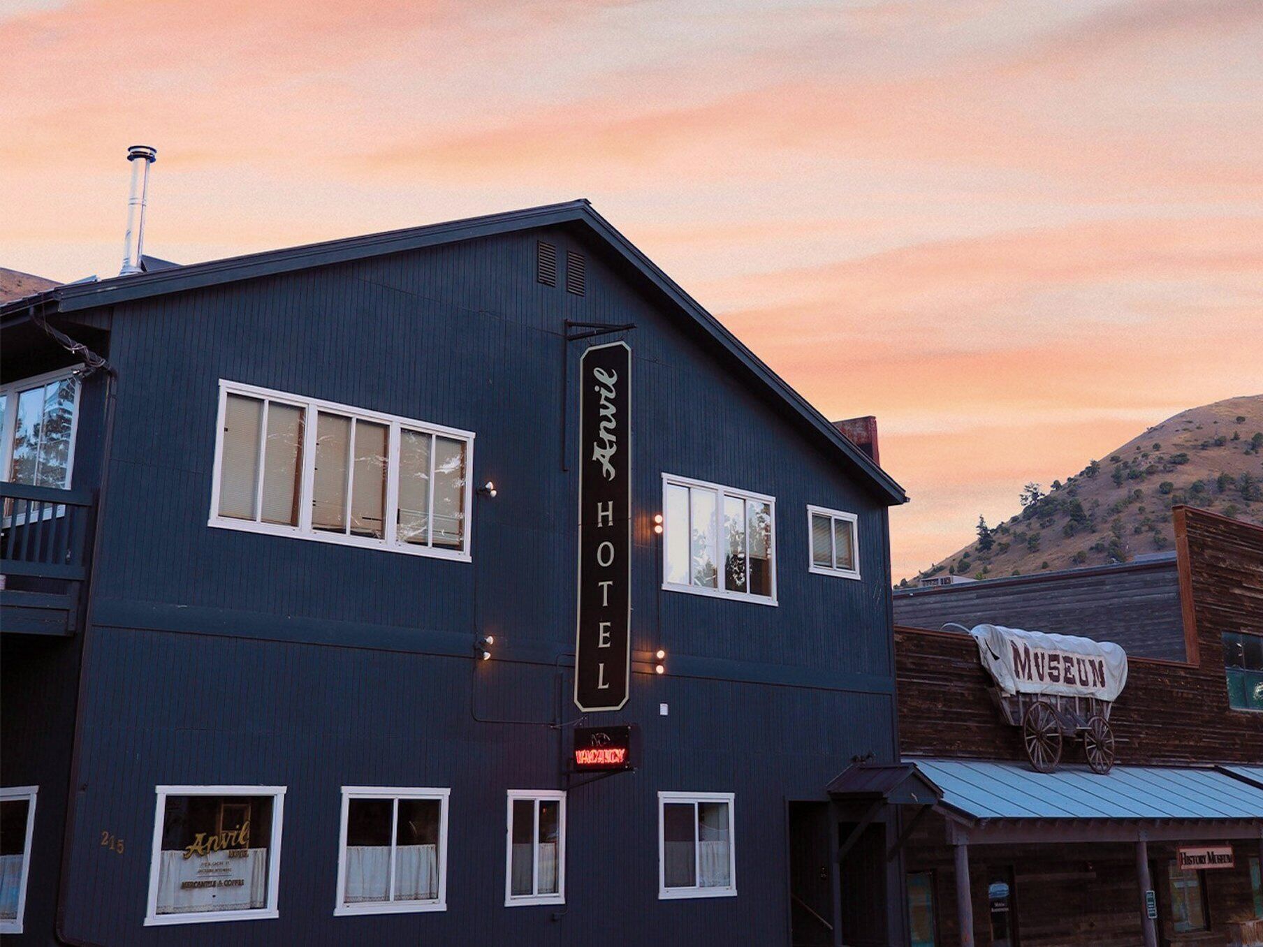 A two-story building with a sign reading 'Anvil Hotel' and a smaller sign for a museum.