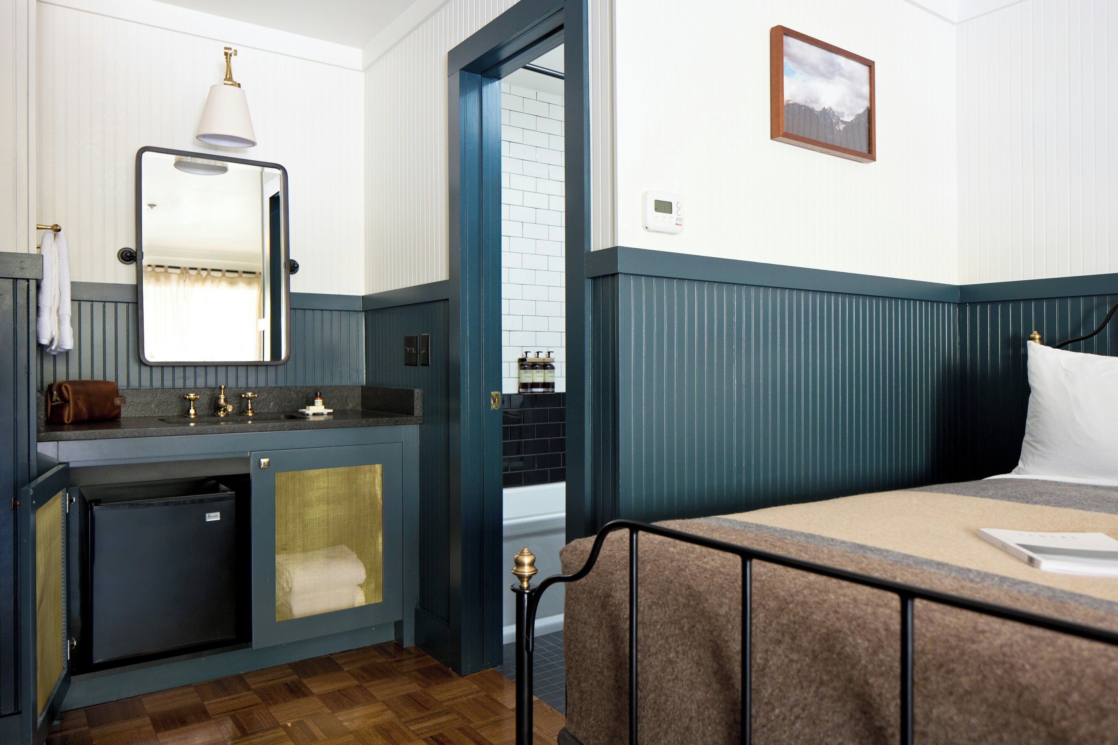 A hotel room with a bed, a small bathroom with a sink, and a mirror.