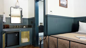 A hotel room with a bed, a small bathroom with a sink, and a mirror.