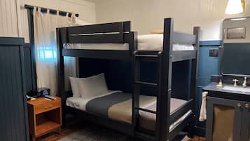 Habitación con literas, un escritorio pequeño, una radio y un espejo.