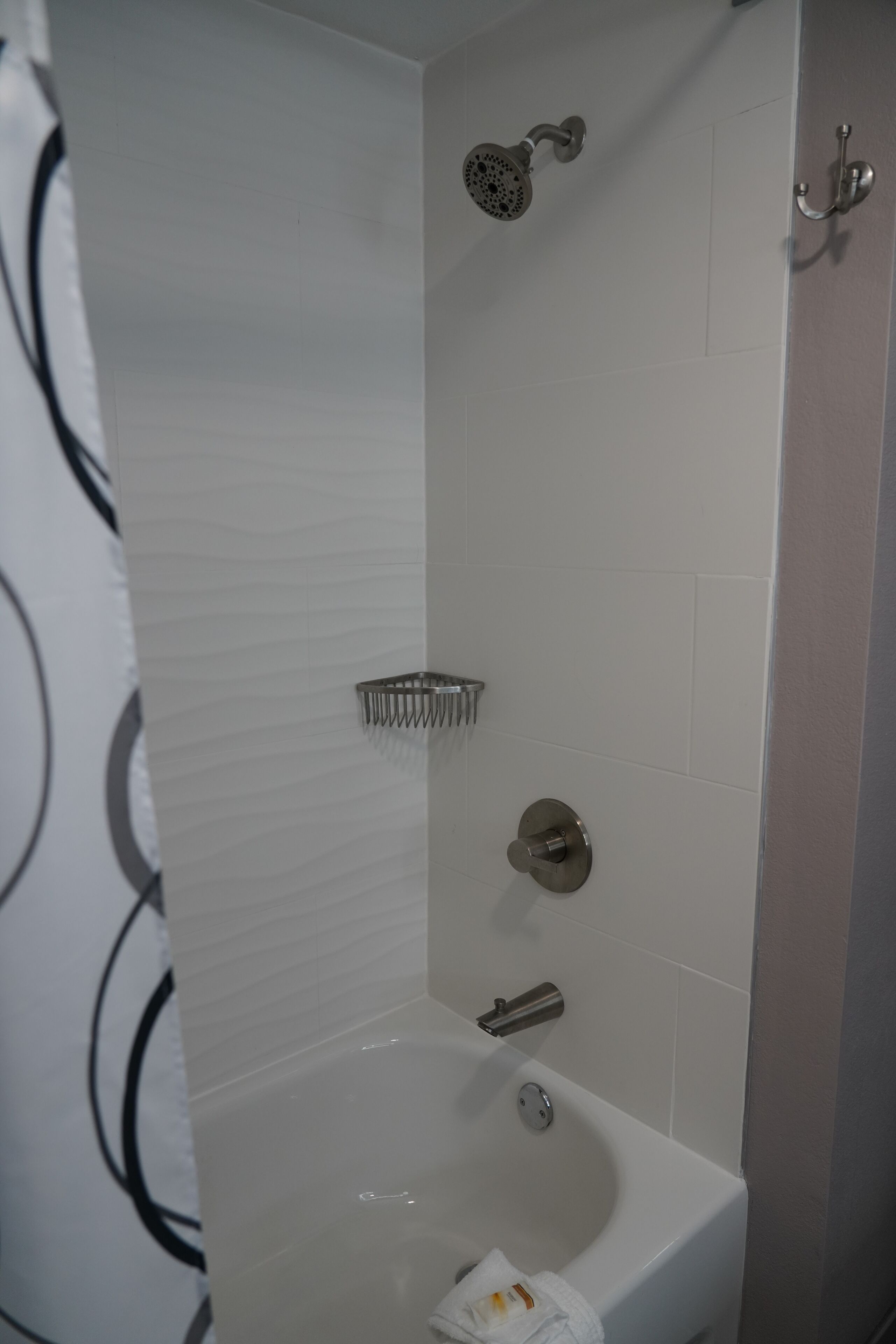 A modern bathroom with a bathtub, shower, and a towel rack.