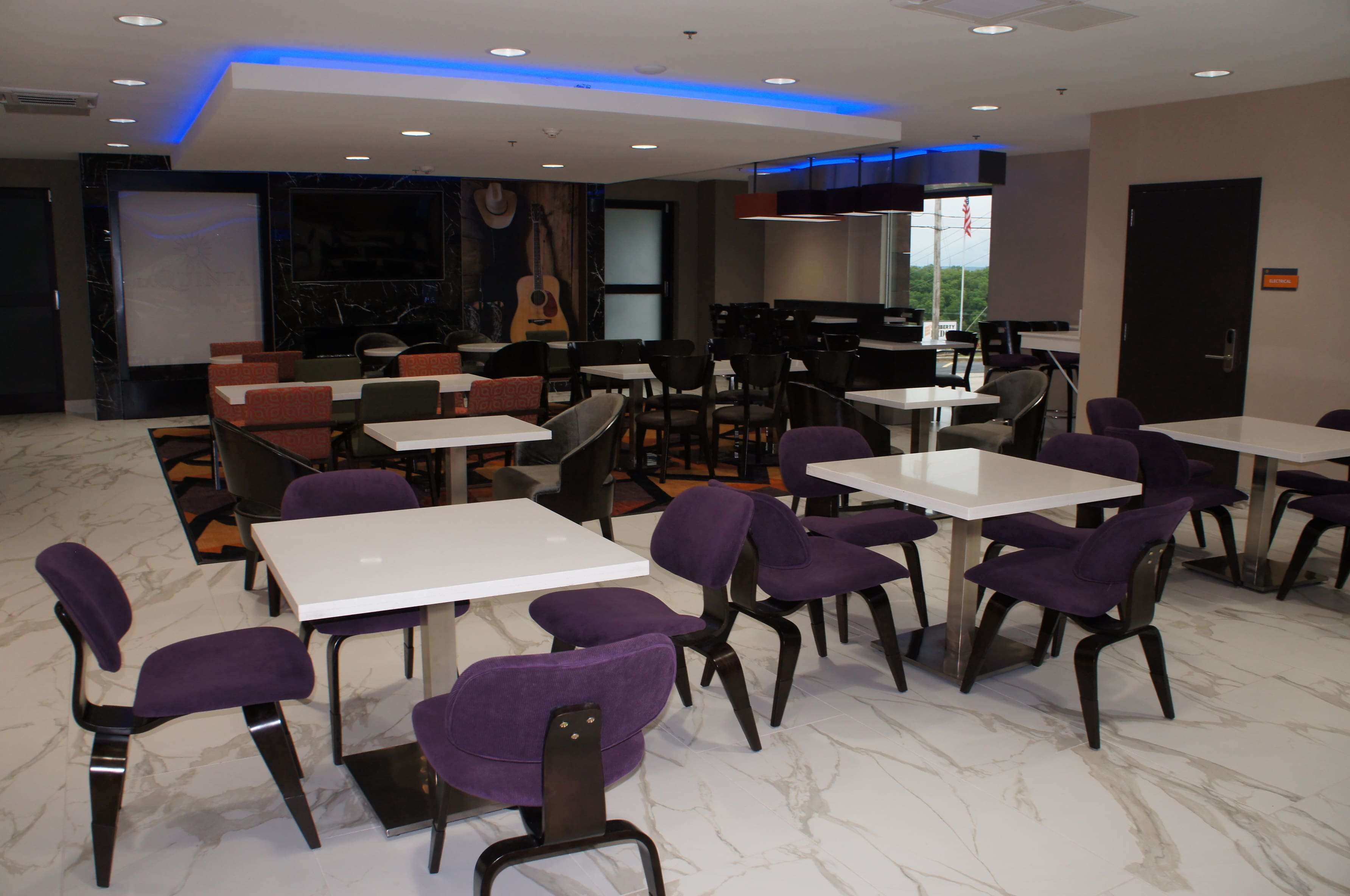 A modern dining area with white tables and purple chairs, marble flooring, and a mural of a guitar on the wall.