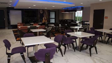 A modern dining area with white tables and purple chairs, marble flooring, and a mural of a guitar on the wall.