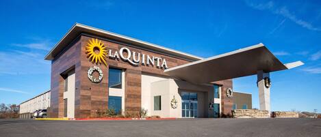 A La Quinta hotel with a modern design, large windows, and a prominent sun logo.