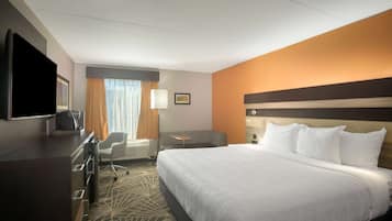 A hotel room with a bed, a desk, a chair, a TV, and a window with curtains.